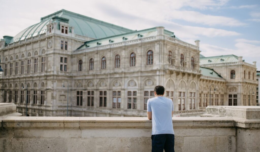 Nomadic Matt leaning on a bridge overlooking the stately Vienna State Opera House in Vienna, Austria