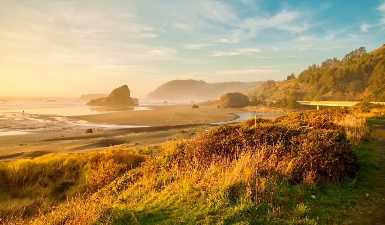 A bright sunrise over a wide, empty beach along the beautiful Oregon coast